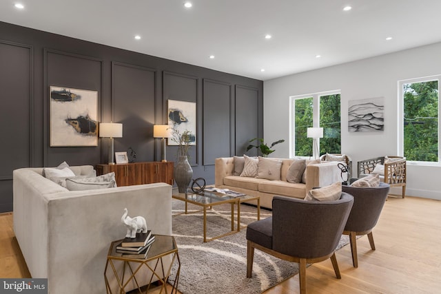 living area featuring light wood-style floors, recessed lighting, and a decorative wall