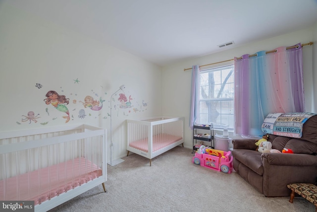 bedroom featuring a nursery area, visible vents, and carpet flooring