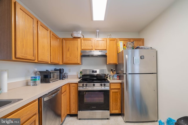 kitchen featuring stainless steel appliances, light countertops, and under cabinet range hood