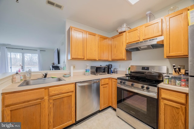 kitchen with visible vents, appliances with stainless steel finishes, light countertops, under cabinet range hood, and a sink