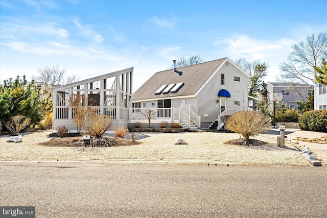 view of front facade featuring roof with shingles and a sunroom