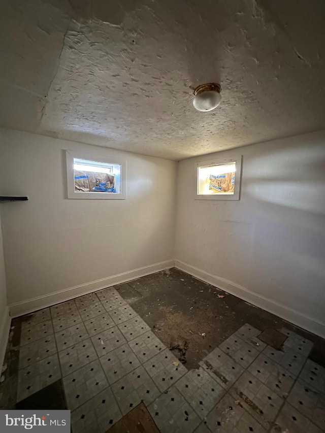 below grade area with baseboards and a textured ceiling