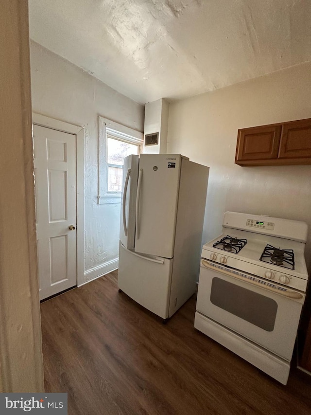 kitchen with white appliances, visible vents, brown cabinetry, dark wood finished floors, and light countertops