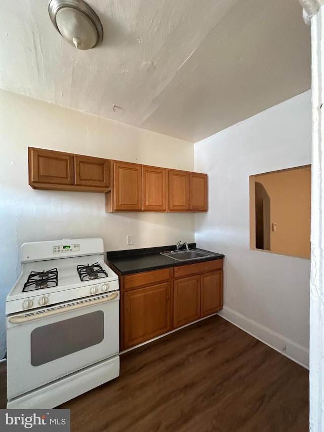 kitchen with dark countertops, white range with gas cooktop, and brown cabinetry