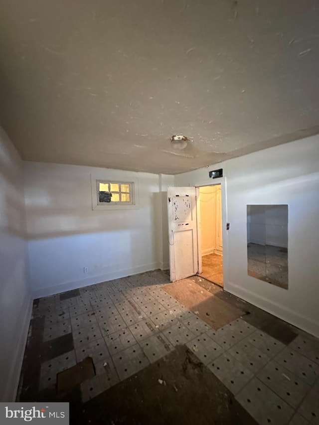 interior space with baseboards and tile patterned floors