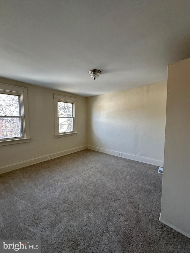 unfurnished room with dark carpet and baseboards