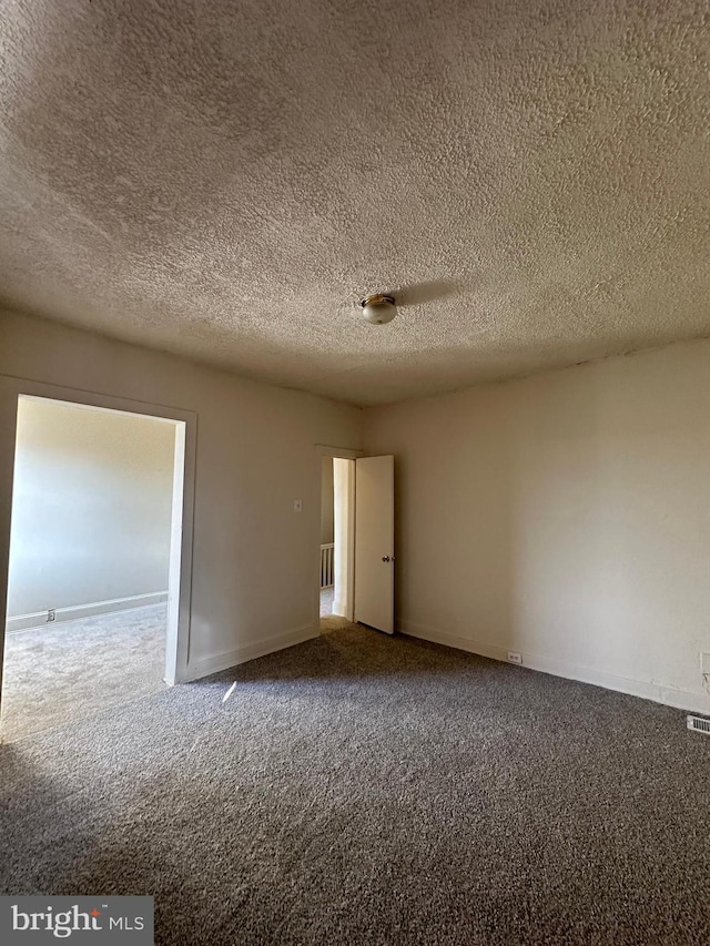 spare room featuring a textured ceiling, carpet floors, and baseboards