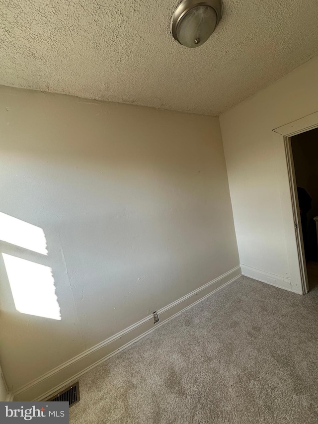 carpeted empty room with visible vents, a textured ceiling, and baseboards