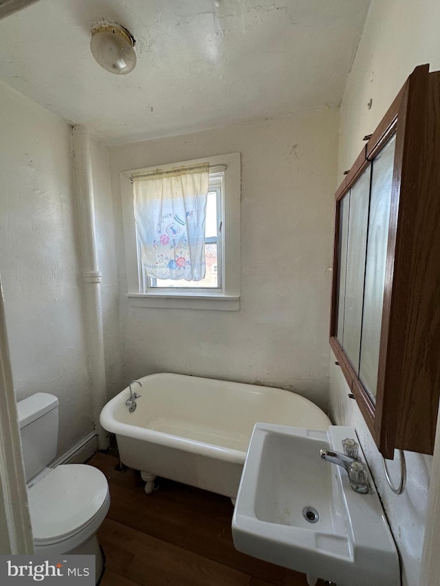 full bathroom with a sink, toilet, a freestanding bath, and wood finished floors