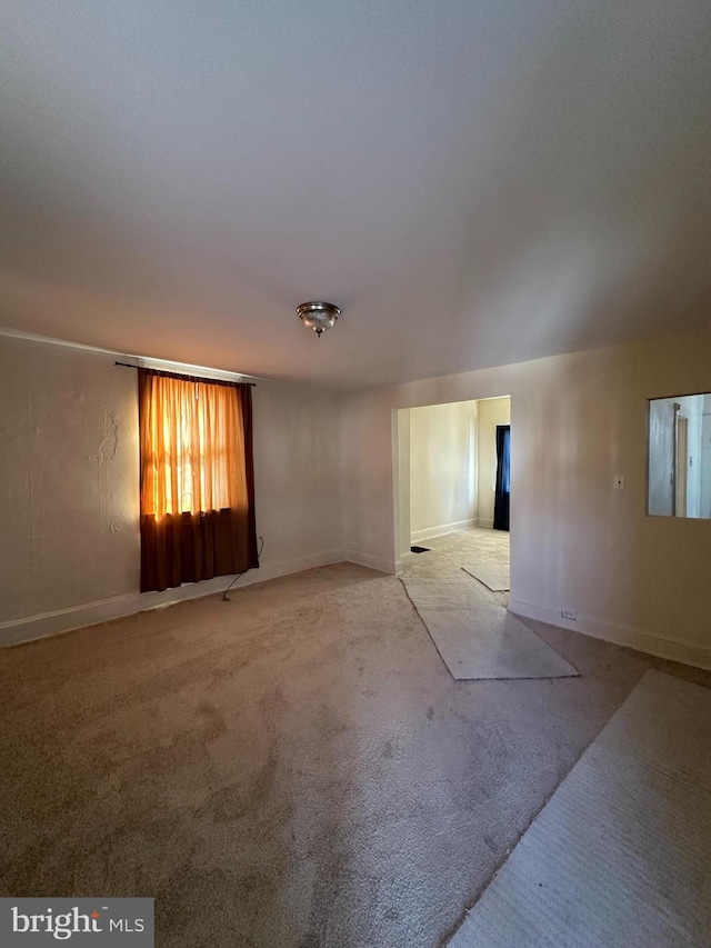 unfurnished room with baseboards and light colored carpet