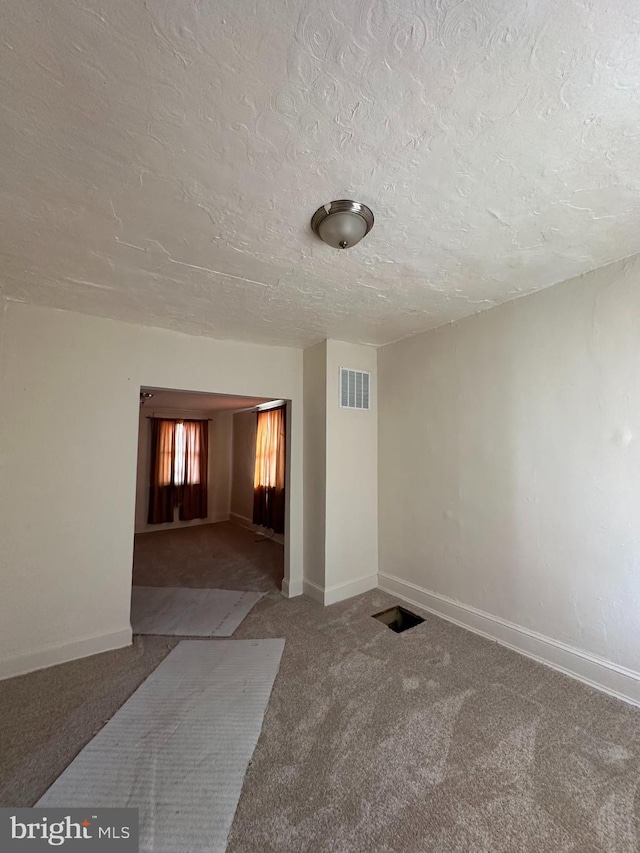 unfurnished room featuring baseboards, visible vents, a textured ceiling, and carpet flooring