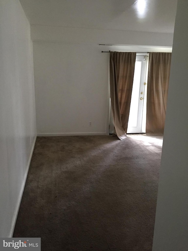 empty room with dark carpet and baseboards