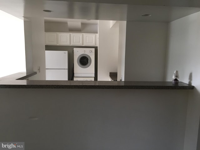 kitchen with freestanding refrigerator, washer / clothes dryer, white cabinets, and dark countertops