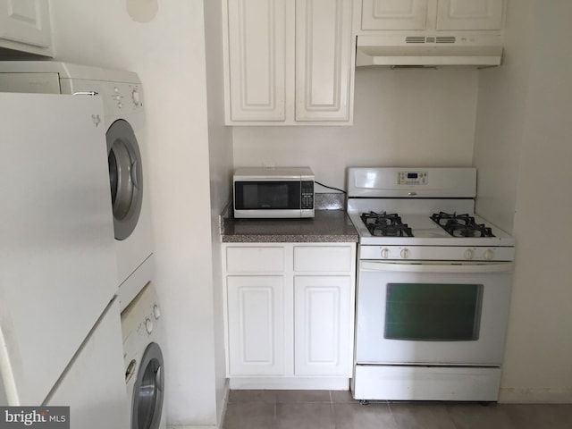 kitchen featuring dark countertops, washer / clothes dryer, stainless steel microwave, white range with gas cooktop, and under cabinet range hood