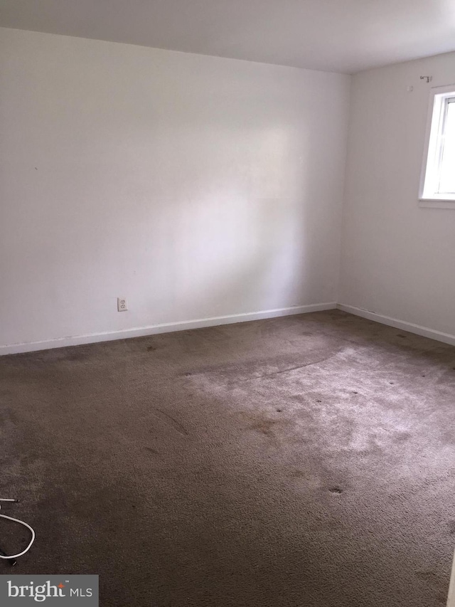 empty room featuring carpet and baseboards