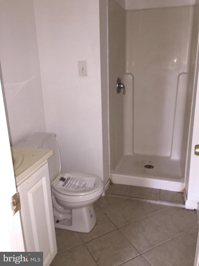 bathroom featuring vanity, a shower stall, toilet, and tile patterned floors