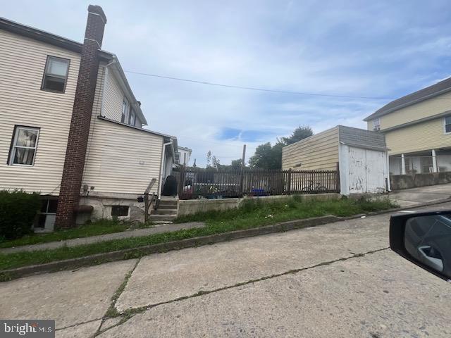 view of side of home featuring a storage shed, an outdoor structure, and fence