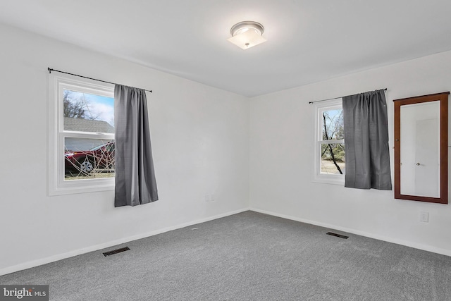 carpeted empty room featuring visible vents and baseboards