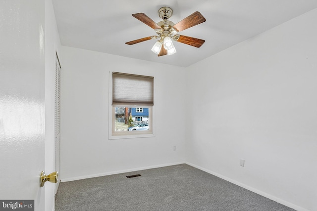 carpeted spare room with visible vents, baseboards, and a ceiling fan