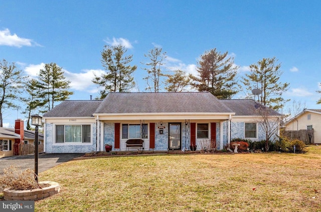 view of front of property featuring covered porch, fence, and a front lawn