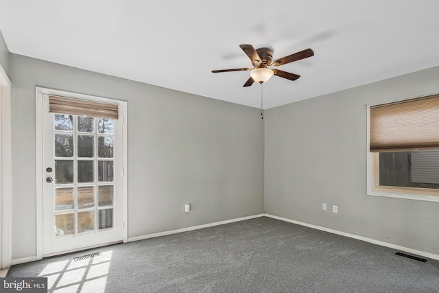 carpeted empty room featuring baseboards, visible vents, and a ceiling fan