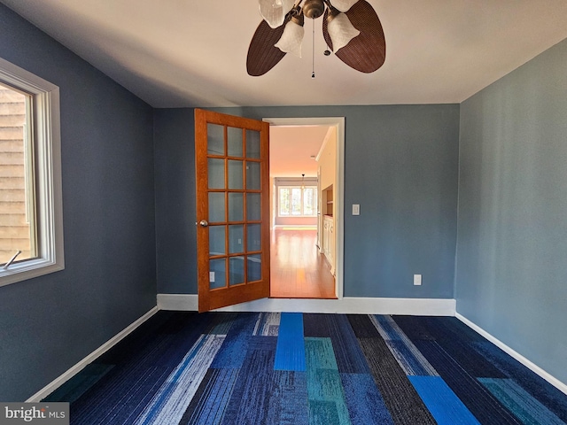 spare room featuring ceiling fan, dark wood-style flooring, and baseboards