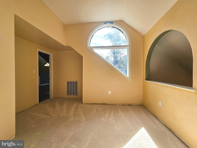 empty room featuring lofted ceiling, carpet, and visible vents