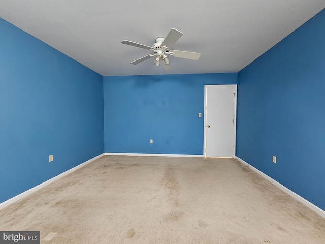 carpeted spare room with a ceiling fan and baseboards