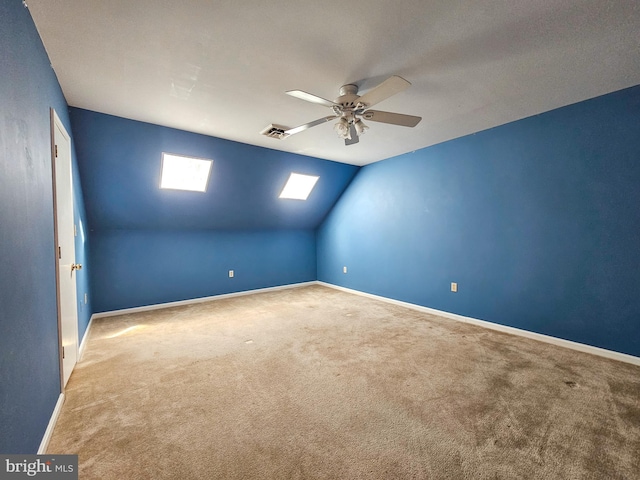 additional living space with a ceiling fan, visible vents, baseboards, lofted ceiling with skylight, and carpet