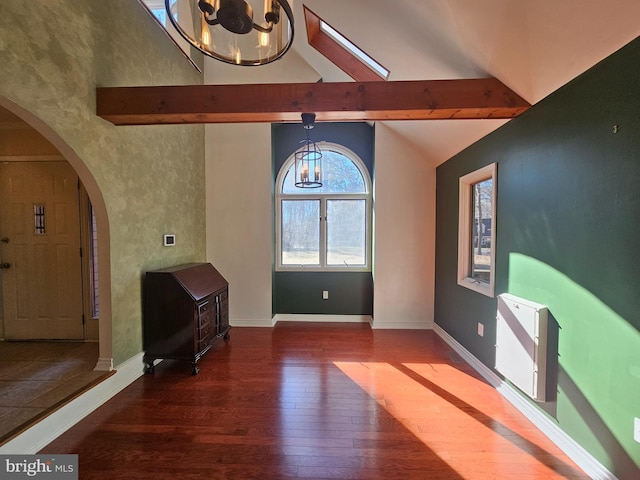 interior space featuring arched walkways, a notable chandelier, wood finished floors, baseboards, and beam ceiling