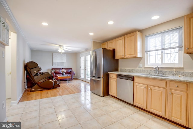 kitchen featuring light tile patterned flooring, stainless steel appliances, a sink, ornamental molding, and light brown cabinetry