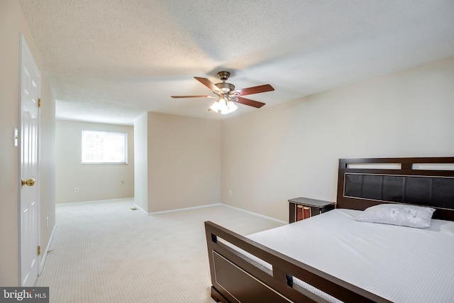 bedroom featuring light colored carpet, ceiling fan, a textured ceiling, and baseboards