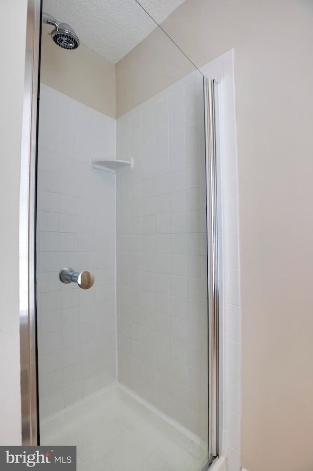 full bathroom with a textured ceiling and a tile shower