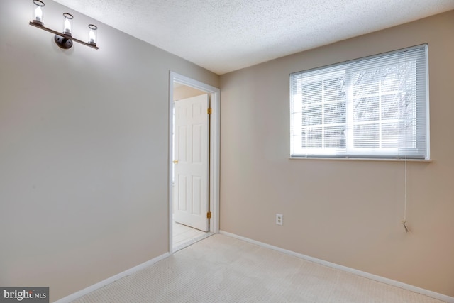 spare room featuring carpet floors, baseboards, and a textured ceiling