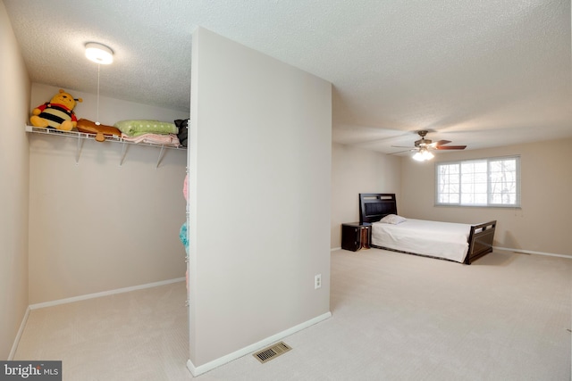 carpeted bedroom featuring a textured ceiling, ceiling fan, visible vents, and baseboards