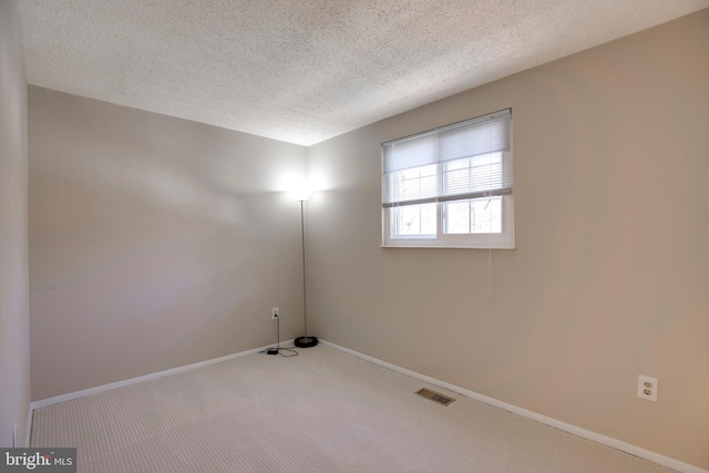 unfurnished room featuring baseboards, carpet, visible vents, and a textured ceiling