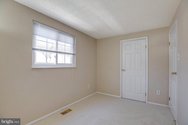 unfurnished bedroom with baseboards, a textured ceiling, visible vents, and carpet flooring