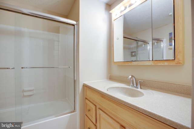 full bathroom featuring shower / bath combination with glass door, a textured ceiling, and vanity