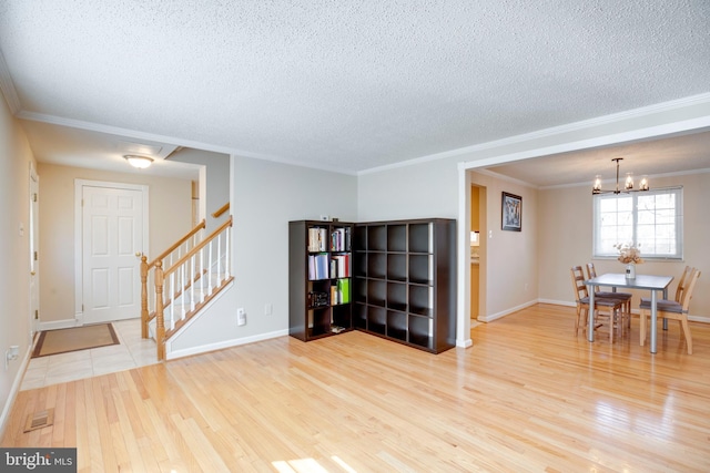 interior space featuring stairway, ornamental molding, wood finished floors, an inviting chandelier, and a textured ceiling