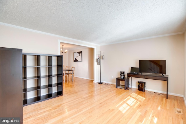 living area with an inviting chandelier, ornamental molding, a textured ceiling, wood finished floors, and baseboards