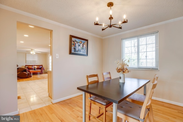 dining space featuring ornamental molding, light wood-type flooring, a textured ceiling, and baseboards