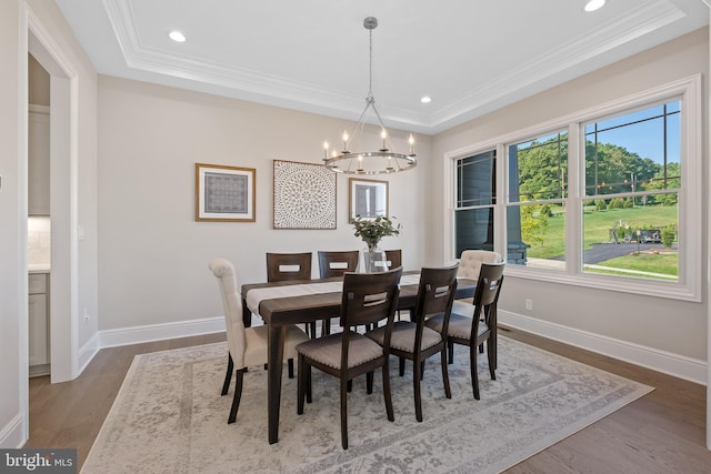 dining area featuring ornamental molding, a tray ceiling, dark wood-type flooring, and baseboards