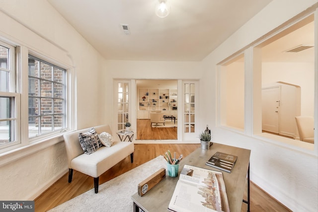 living area with visible vents and wood finished floors