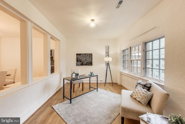 office space with light wood-type flooring, visible vents, and baseboards