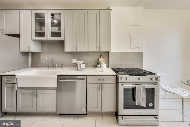 kitchen with stainless steel appliances, gray cabinets, light countertops, and glass insert cabinets