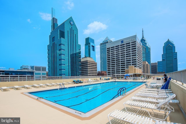 community pool featuring fence, a city view, and a patio