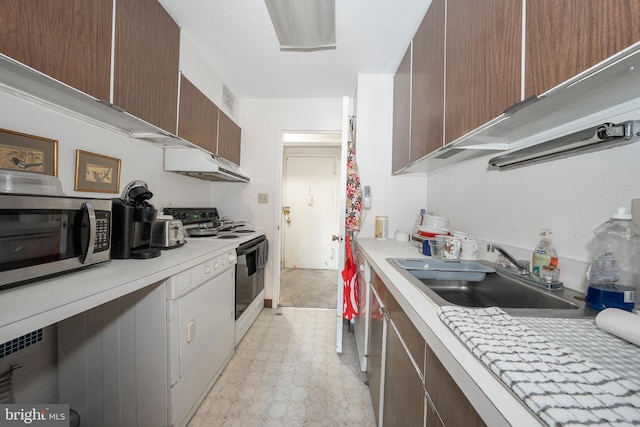 kitchen featuring light countertops, stainless steel microwave, a sink, and electric range oven