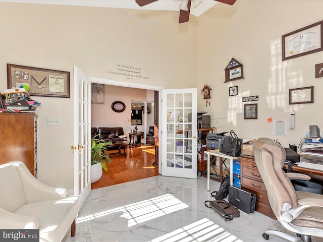 office space with french doors, a high ceiling, marble finish floor, and a ceiling fan