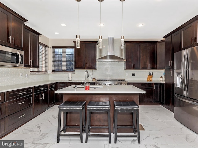 kitchen featuring a breakfast bar area, a sink, stainless steel appliances, wall chimney range hood, and marble finish floor