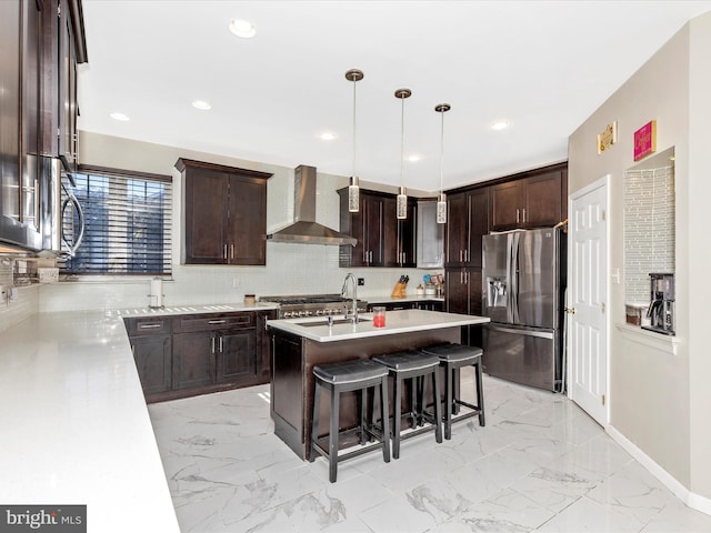 kitchen with marble finish floor, appliances with stainless steel finishes, a breakfast bar area, wall chimney exhaust hood, and dark brown cabinets